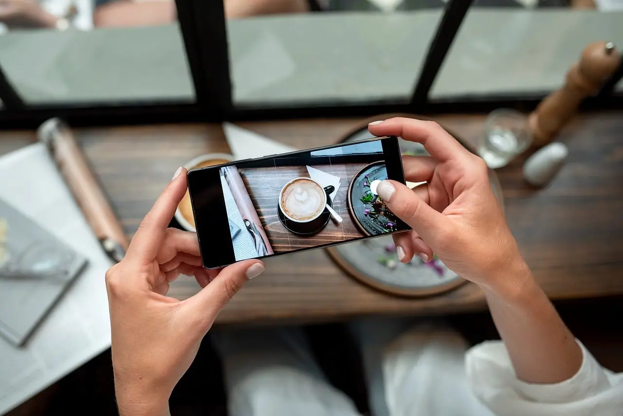 Mains tenant un smartphone au-dessus d'une table de café