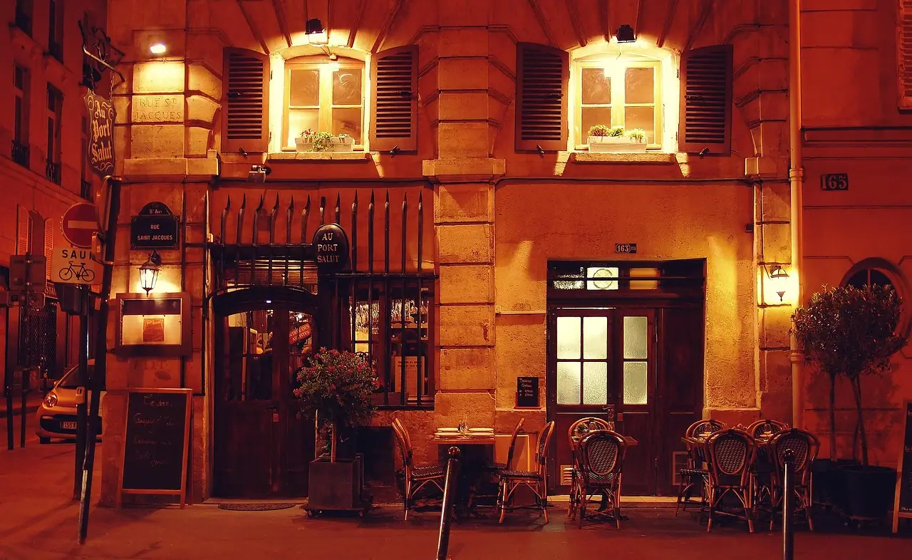 Façade de restaurant éclairée en soirée, terrasse dans la rue